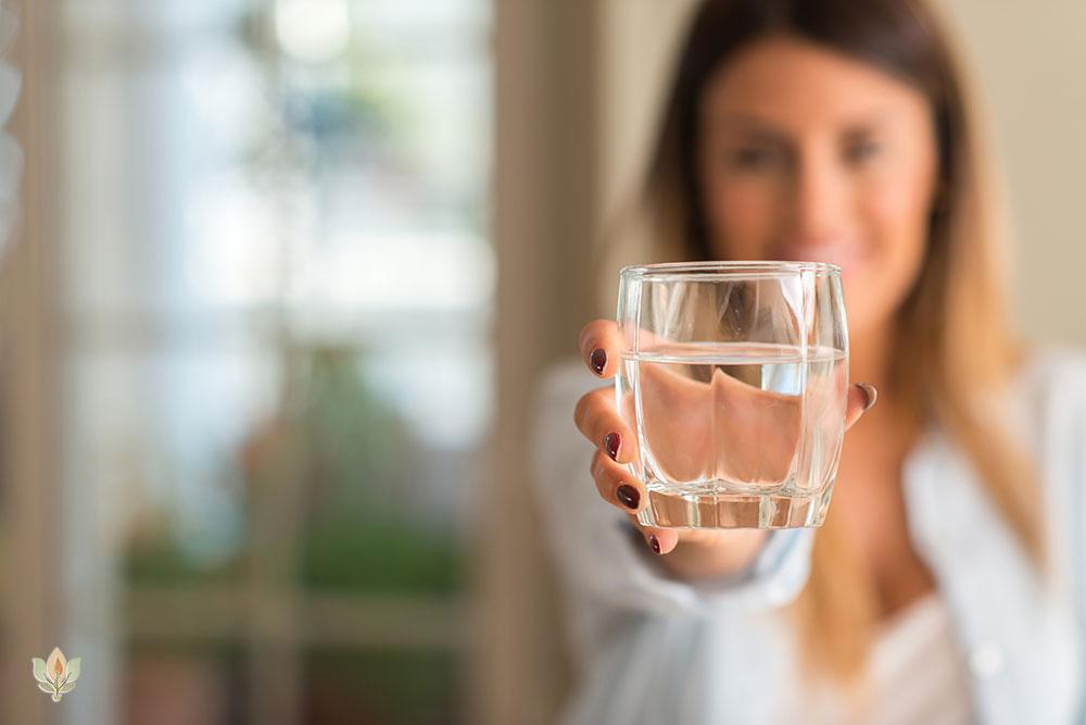 Woman holding a glass of pure water from Kangen